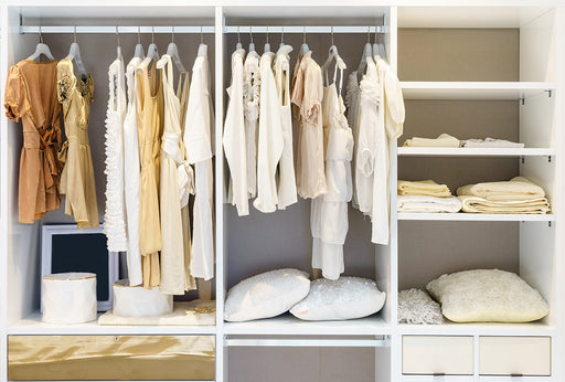 a color coordinated closet full of dresses and tops