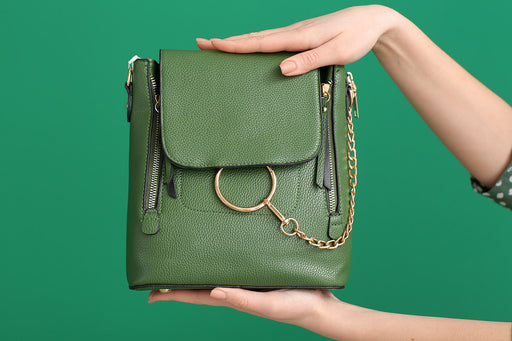 a leather green handbag with a gold chain on a green background