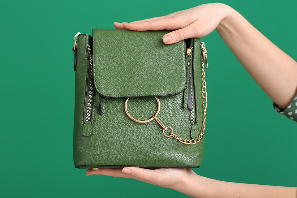 a leather green handbag with a gold chain on a green background