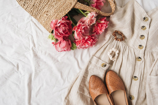 a linen summer dress in a neutral colour, shown with shoes and a basket of flowers