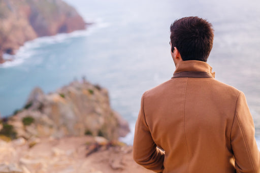 a man in a woollen coat looking out to the sea