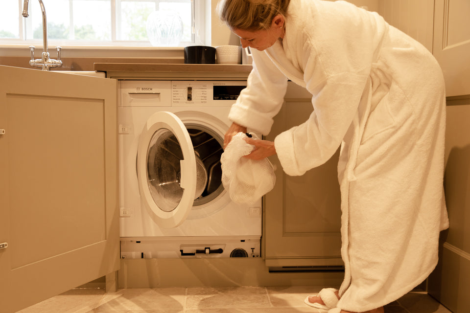  a mesh bag of laundry being put in the washing machine