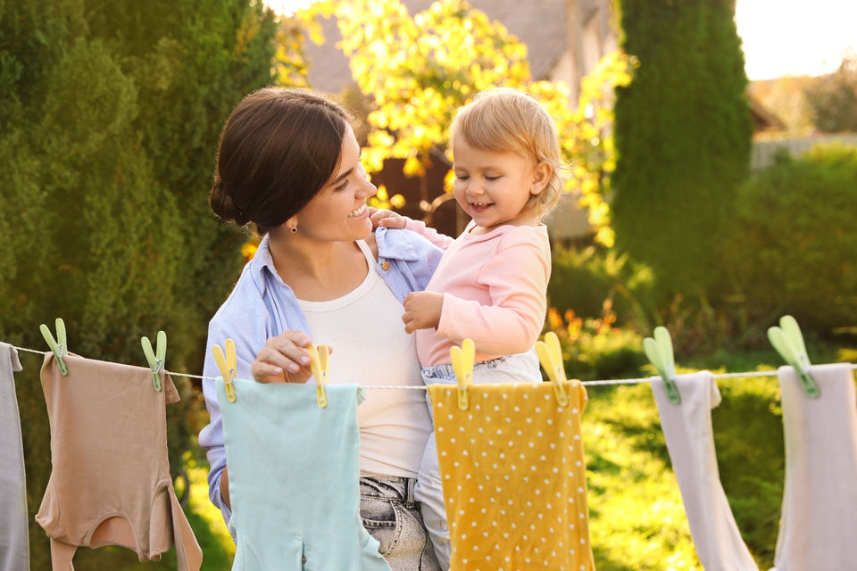 a mother and child hanging clothes to dry on a shaded part of a washing line