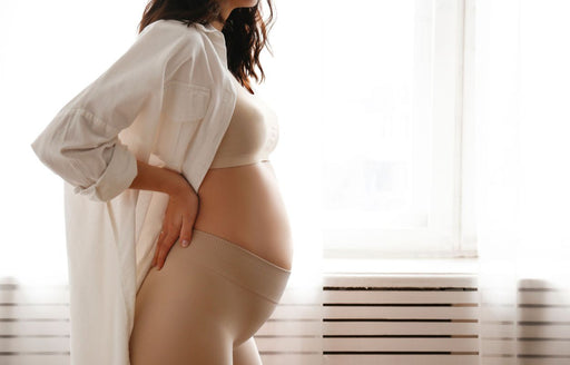 a pregnant woman wearing a long shirt over comfortable stretchy yoga pants and bra top