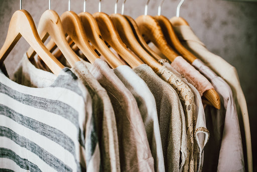 a selection of clothing on wooden hangers