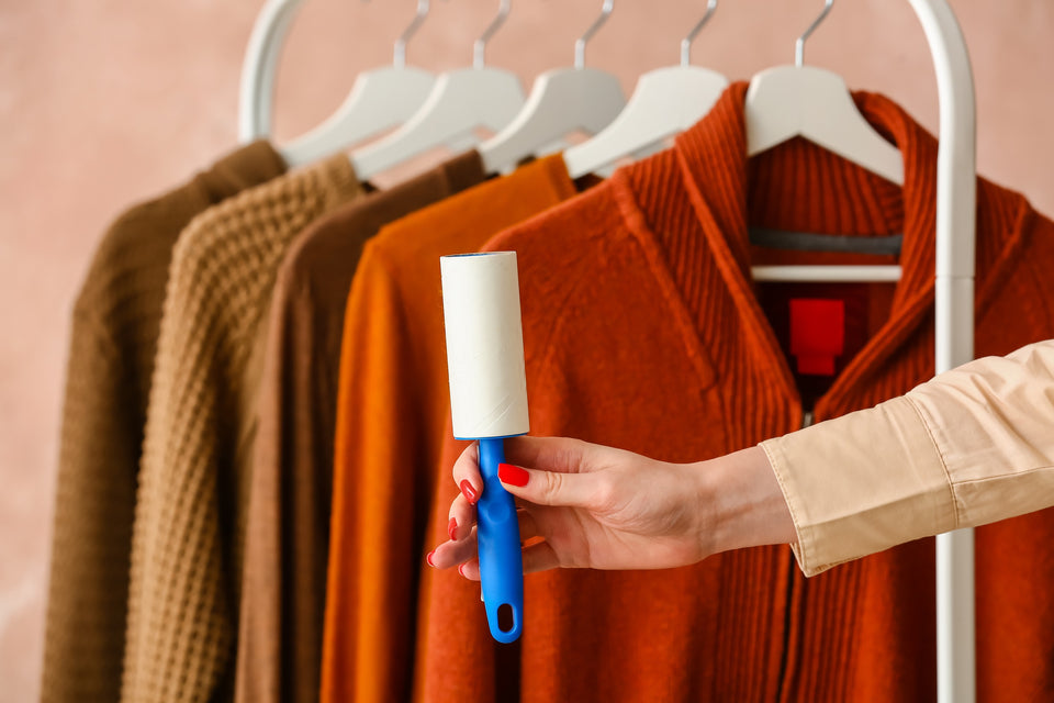 a selection of woollen sweaters on a clothes rail with a lint roller