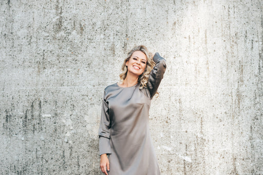 a smiling beautiful woman in a grey silk dress