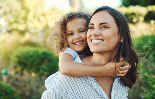 a smiling woman giving her happy daughter a piggyback