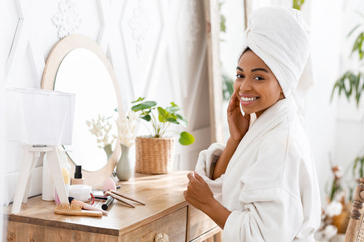 a stunning woman in her bathrobe sitting at her dressing room table with her makeup