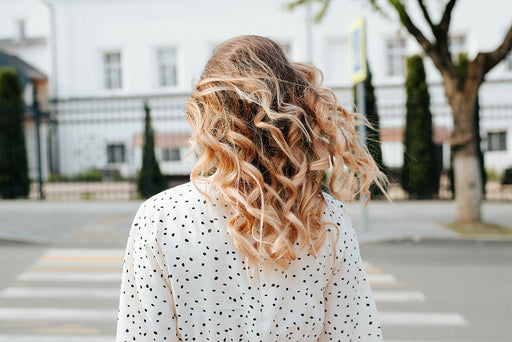 a wavy haired woman with her back to the camera, wearing a polka dot top