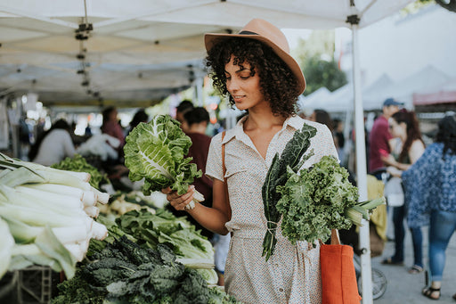 a woman choosing organic vegetables at an outdoor market