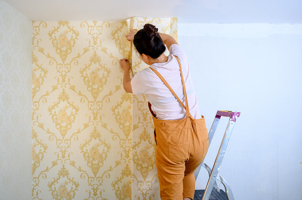 a woman hanging wallpaper