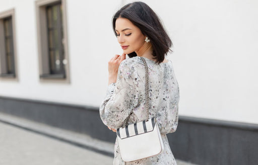 a woman in a floral dress with a white handbag over her shoulder