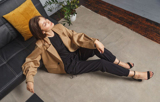 a woman in a tan oversized blazer and black top and leggings with black high heeled sandals