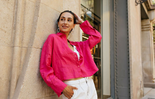a woman in her thirties wearing cream pants and a fuchsia pink shirt