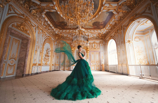 a woman in palatial surroundings wearing a stunning green dress with layers of green feathers