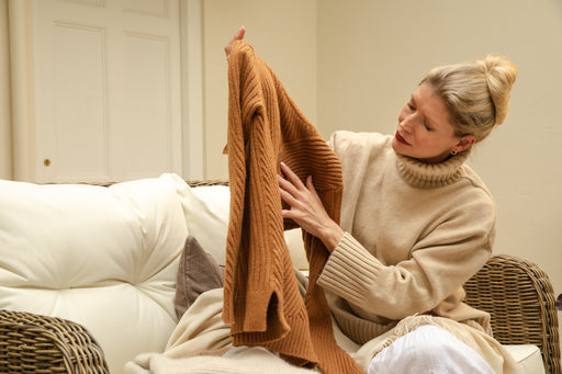 a woman inspecting her rust-coloured woollen sweater