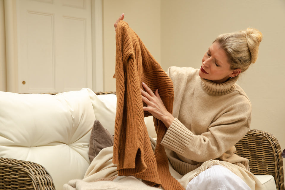 a woman inspecting her rust-coloured woollen sweater