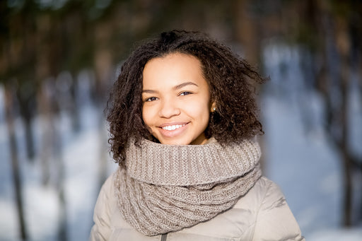 a woman keeping warm in a pale brown wool neck warmer and padded coat