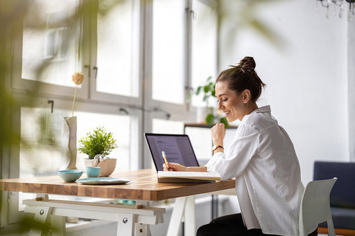 a woman researching on her lap top and making notes