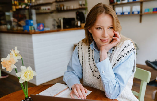 a woman sitting in a cafe wearing a blue shirt and a knitted oversized vest