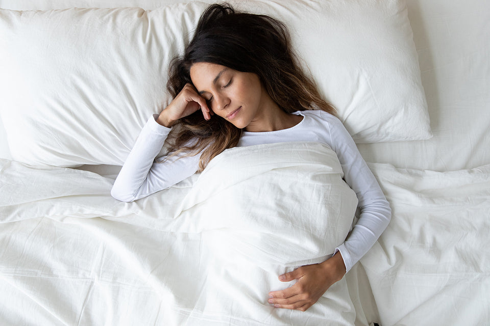 a woman sleeping in bleached white cotton bed linen