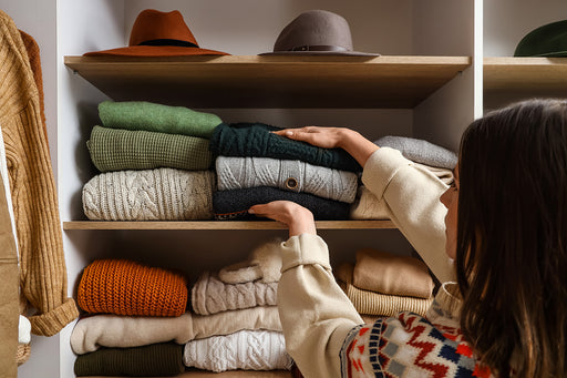 a woman sorting out her shelf of woolen winter knits