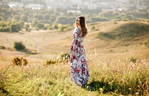 a woman standing in a field wearing a floral printed long sleeved maxi dress