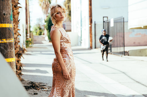 a woman standing in a street wearing a peach-colored glitter sleeveless dress