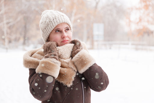 a woman standing in the snow wearing a sheepskin coat