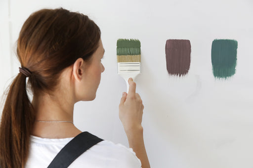 a woman testing paint colours on a white wall