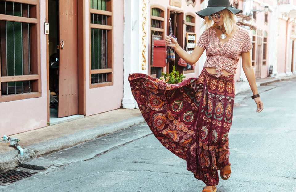a woman wearing a boho style printed top and long skirt
