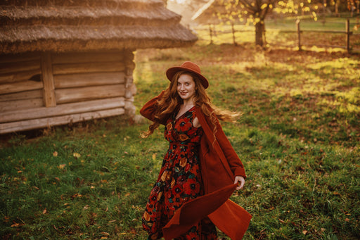 a woman wearing a brightly coloured dress under a rust-coloured woollen long cardigan