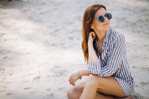 a woman wearing a casual striped linen shirt over her swimwear