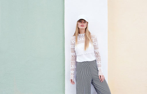 the a woman wearing a lace blouse paired with black and white striped culottes