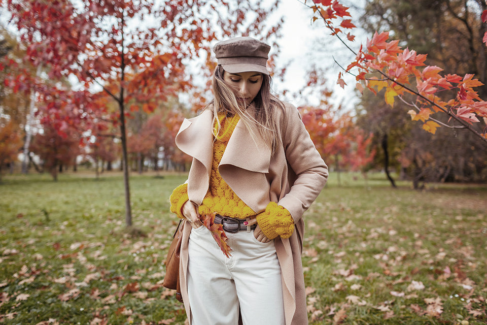 a woman wearing a stylish hat and coat and yellow knit sweater