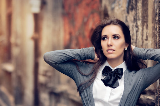 a woman wearing a white shirt black bow tie with a grey cardigan
