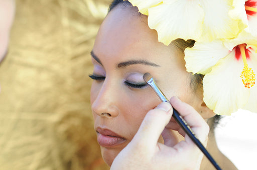 a woman with hibiscus in her hair having her makeup done