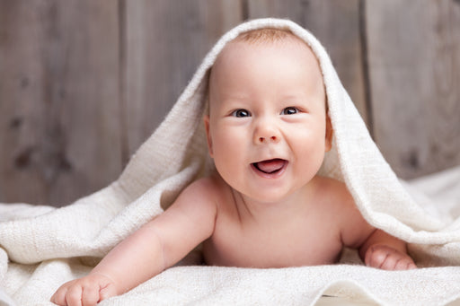 a cute baby peeking out from under a wool blanket