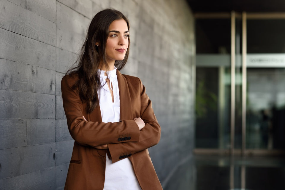 a stylish woman wearing a brown blazer and white shirt