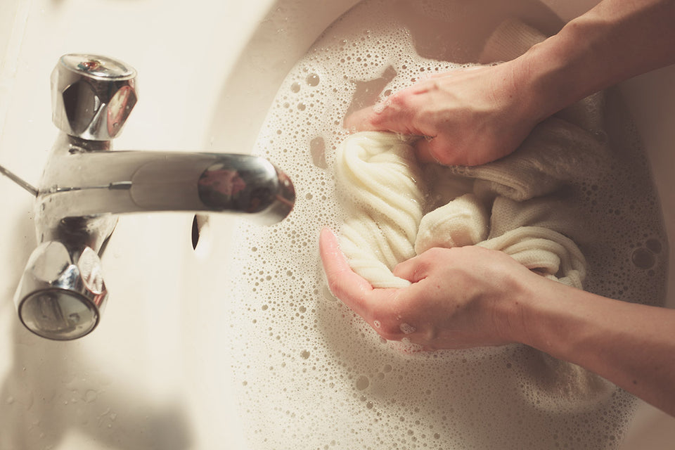 cream woolens being hand washed in a sink