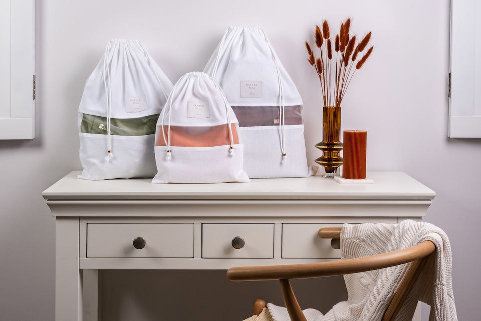 a set of small, medium and a large dust bag with purses inside sitting on a side table