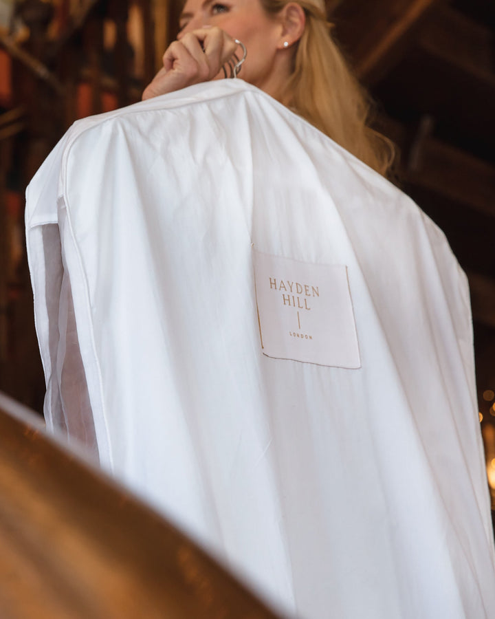 a woman carrying a hanging garment bag over her shoulder
