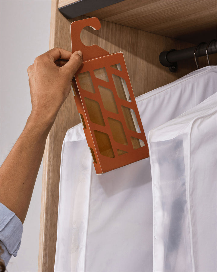 a moth trap being hung on a clothing rail next to hanging garment bags
