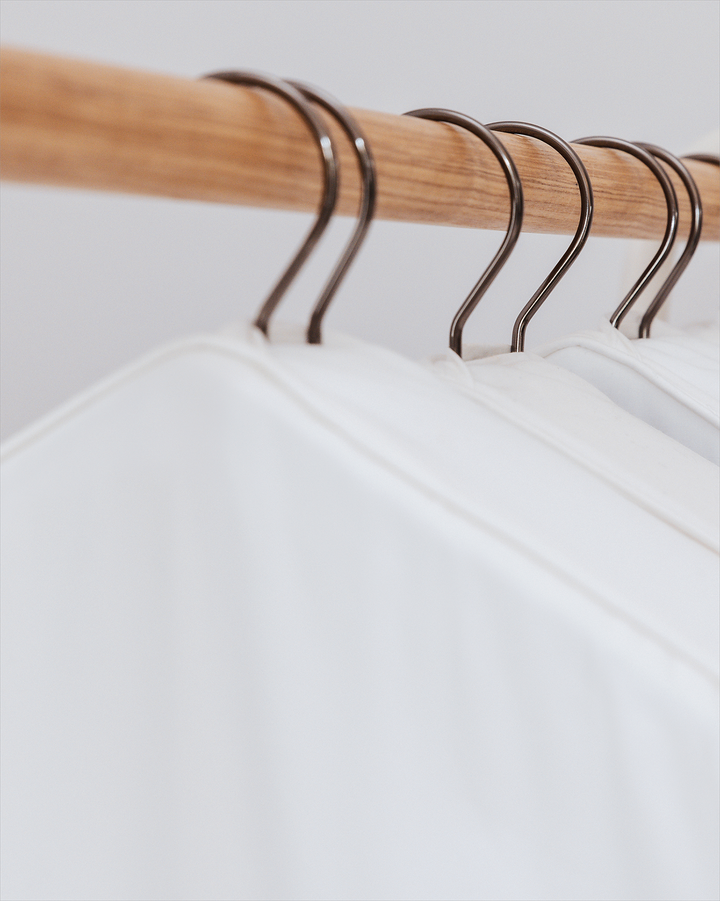 a close up of tops of storage bags on hangers on a wooden rail