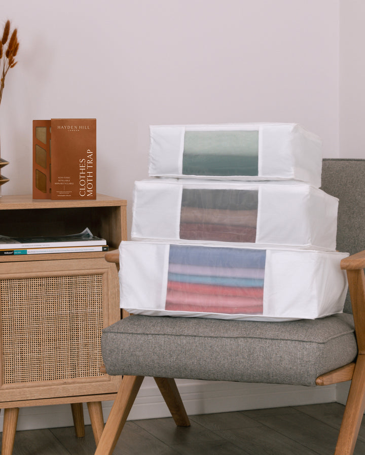 the large, extra large and double extra large storage bags on a chair with a Clothes Moth Trap sitting next to them on a side table
