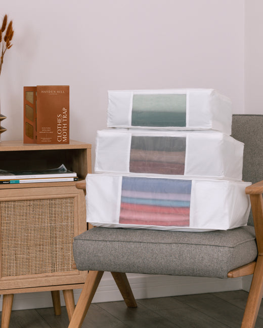 the large, extra large and double extra large storage bags on a chair with a Clothes Moth Trap sitting next to them on a side table