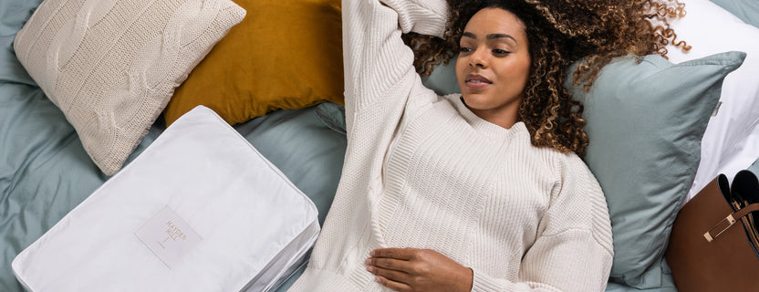 Lady on a bed with a handbag and clothes storage bag
