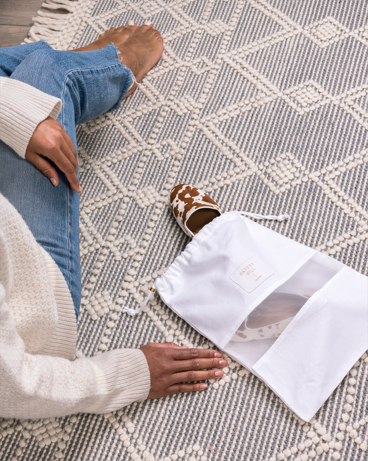 a view looking down over a person's should looking at a dust bag lying on a carpet with shoes poking out