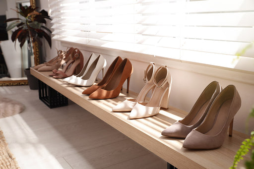 high-heeled pumps and sandals neatly organized in a row on a low bench